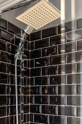 a shower in a bathroom with black tiles at Le Sainte-Marie - Vieux-Terrebonne in Terrebonne