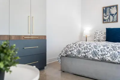 a bedroom with a bed and a dresser with a blue and white bedspread at Le Sainte-Marie - Vieux-Terrebonne in Terrebonne