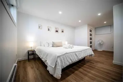 a white bedroom with a large bed with white sheets at Villa luxueuse avec vue sur le fleuve Villa GrandeCasa in Trois-Rivières