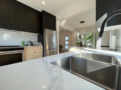 a kitchen with a stainless steel sink and appliances at Villa luxueuse avec vue sur le fleuve Villa GrandeCasa in Trois-Rivières