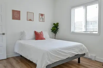a white bedroom with a bed with white sheets and a window at Villa luxueuse avec vue sur le fleuve Villa GrandeCasa in Trois-Rivières