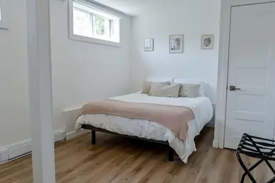 a white bedroom with a bed and a window at Villa luxueuse avec vue sur le fleuve Villa GrandeCasa in Trois-Rivières