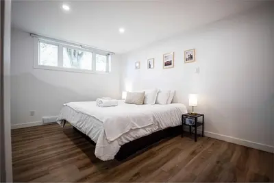 a white bedroom with a large bed and a window at Villa luxueuse avec vue sur le fleuve Villa GrandeCasa in Trois-Rivières