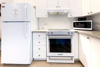 a white kitchen with a stove and a microwave at AFRICA - SelfCheckIn - Plateau - St-Laurent in Montréal