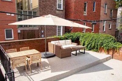 a patio with an umbrella and a couch and a table at POP - SelfCheckIn - Rooftop - Terraces - St-Denis in Montréal