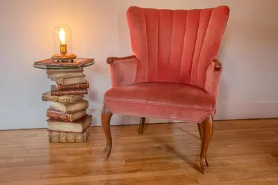 a red chair next to a stack of books and a candle at FICTION - SelfCheckIn - Rooftop - Terraces - St-Denis in Montréal