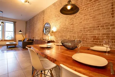 a dining room with a brick wall and a wooden table at VINTAGE - SelfCheckIn - Rooftop - Terraces - St-Denis in Montréal