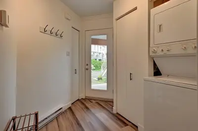 a hallway with white walls and wooden floors and a door at *Nouveauté* Foyer au bois, Plage, Montagne et + in Magog-Orford