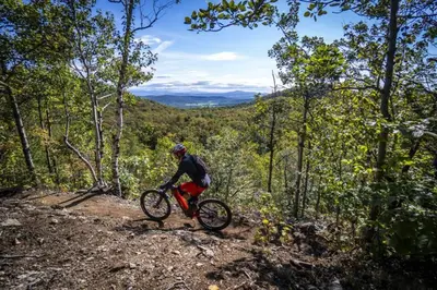 a man riding a bike on a trail in the woods at *Nouveauté* Foyer au bois, Plage, Montagne et + in Magog-Orford