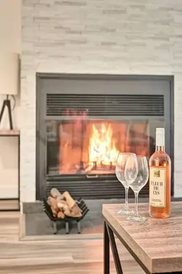a bottle of wine and two glasses on a table in front of a fireplace at *Nouveauté* Foyer au bois, Plage, Montagne et + in Magog-Orford