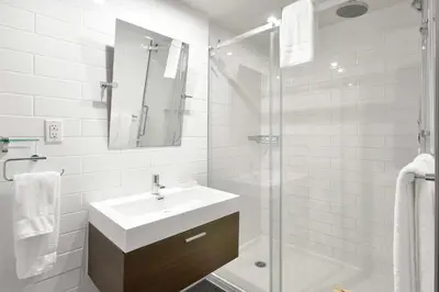 a white bathroom with a sink and a shower at Hotel Épik Montréal in Montréal