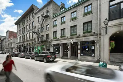 a white car driving down a city street with buildings at Hotel Épik Montréal in Montréal