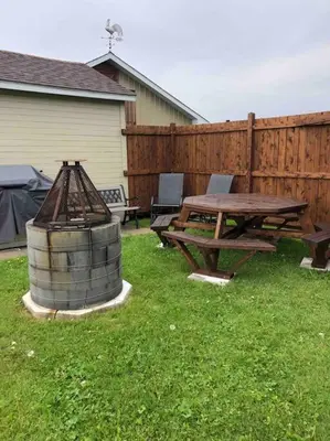 a picnic table and a grill next to a fence at Spacieux 4,5 Parfait pour des Vacances Confortables ! in Lac-Mégantic
