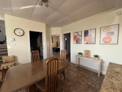 a dining room with a table and a clock on the wall at Spacieux 4,5 Parfait pour des Vacances Confortables ! in Lac-Mégantic
