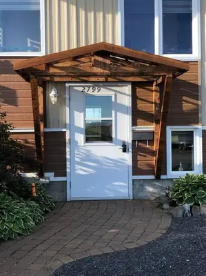 a house with a white door with a wooden roof at Spacieux 4,5 Parfait pour des Vacances Confortables ! in Lac-Mégantic