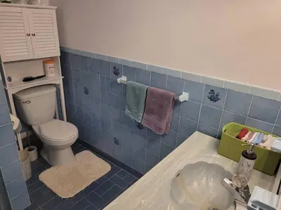 a blue tiled bathroom with a toilet and a sink at QUIET Appartment near Montreal CITQ 3O9764 in Longueuil