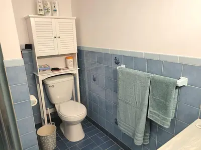 a blue tiled bathroom with a toilet and towels at QUIET Appartment near Montreal CITQ 3O9764 in Longueuil