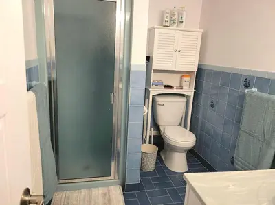 a blue tiled bathroom with a toilet and a shower at QUIET Appartment near Montreal CITQ 3O9764 in Longueuil