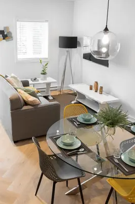 a living room with a glass table and chairs at Le Karina - Vieux-Terrebonne in Terrebonne