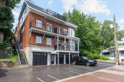 a black car parked in front of a brick building at Le Karina - Vieux-Terrebonne in Terrebonne