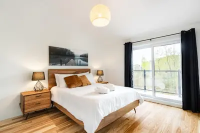 a bedroom with a bed and a large window at Le Memph Aigle spacious comfortable condo cottage eco friendly 3 bedrooms - hot tub & pool Memphrémagog Lake in Magog-Orford