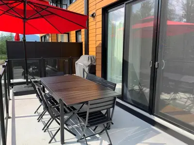a wooden table and chairs with a red umbrella at Le Memph Aigle spacious comfortable condo cottage eco friendly 3 bedrooms - hot tub & pool Memphrémagog Lake in Magog-Orford