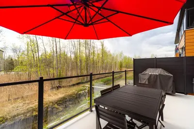 a table and chairs on a balcony with a red umbrella at Le Memph Aigle spacious comfortable condo cottage eco friendly 3 bedrooms - hot tub & pool Memphrémagog Lake in Magog-Orford
