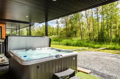 a hot tub in the middle of a yard at Le Memph Aigle spacious comfortable condo cottage eco friendly 3 bedrooms - hot tub & pool Memphrémagog Lake in Magog-Orford