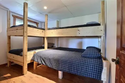 two bunk beds in a room with a bed at Chalet en bois rond in Saint-Herménégilde