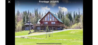 a large wooden house on a green field at Chalet en bois rond in Saint-Herménégilde