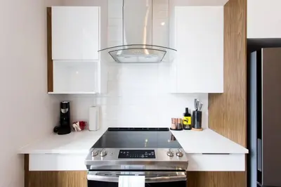 a kitchen with a stove and white cabinets at Fresh 1 Bdr in the Heart of Mile End by Denstays in Montréal