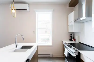 a white kitchen with a sink and a window at Fresh 1 Bdr in the Heart of Mile End by Denstays in Montréal