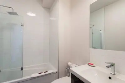a white bathroom with a toilet and a sink at Fresh 1 Bdr in the Heart of Mile End by Denstays in Montréal