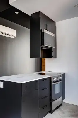 a kitchen with black cabinets and a stove at Le Black & White - Vieux-Terrebonne in Terrebonne