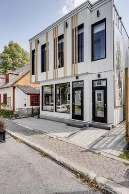 a white building with black windows on a street at Le Black & White - Vieux-Terrebonne in Terrebonne