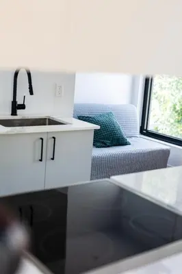 a kitchen and living room with a sink and a couch at Le Virtuose - Vieux-Terrebonne in Terrebonne