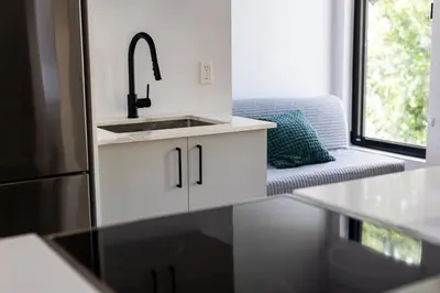 a kitchen with a sink and a couch at Le Virtuose - Vieux-Terrebonne in Terrebonne