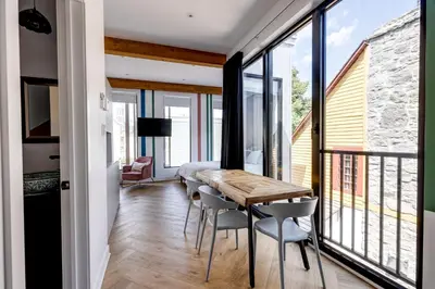 a dining room with a table and chairs and windows at Le Virtuose - Vieux-Terrebonne in Terrebonne