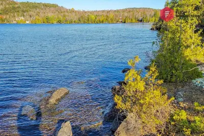 a large lake with a red house on the shore at Aux Berges du Pont Suspendu / Grand Lac Brompton in Saint Denis de Brompton