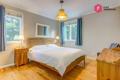 a bedroom with a large bed and two windows at Aux Berges du Pont Suspendu / Grand Lac Brompton in Saint Denis de Brompton