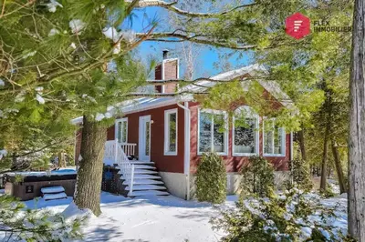 a red house with snow in front of it at Aux Berges du Pont Suspendu / Grand Lac Brompton in Saint Denis de Brompton