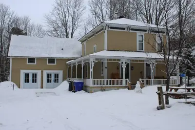 a house with snow on the ground in front of it at House & loft, pool table, ping-pong, fireplace, AC in Ayer's Cliff