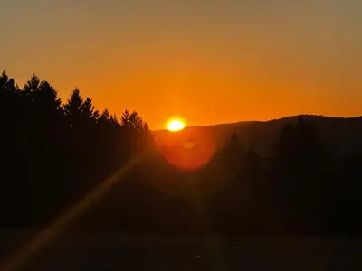 a sunset in the mountains with trees in the foreground at House & loft, pool table, ping-pong, fireplace, AC in Ayer's Cliff