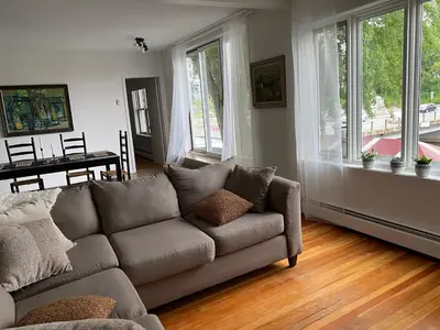a living room with a couch and a table and windows at Auberge des Cantons in Magog-Orford