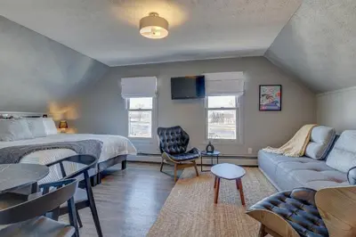 a bedroom with a bed and a living room with a couch at Auberge des Cantons in Magog-Orford