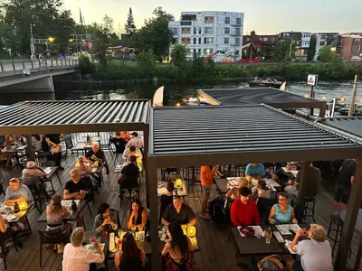 a group of people sitting at tables on a deck at Auberge des Cantons in Magog-Orford