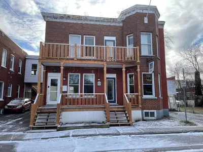 a house with a deck on the front of it at Auberge du Monde in Trois-Rivières