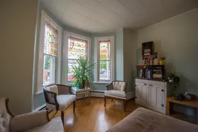 a living room with a couch and chairs and windows at Auberge du Monde in Trois-Rivières