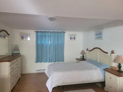 a bedroom with a bed and a blue curtain at L ' Arlequin Suite et logement in Vaudreuil-Dorion
