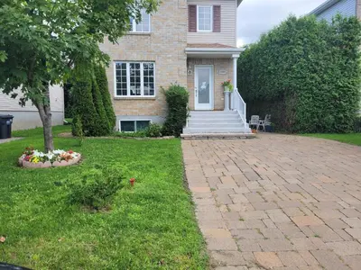 a house with a brick driveway in the yard at L ' Arlequin Suite et logement in Vaudreuil-Dorion